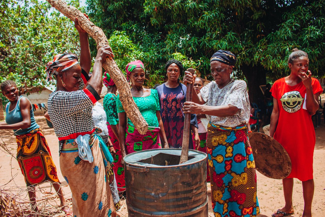 services-03 Group of women in colorful traditional clothing cooking outdoors.