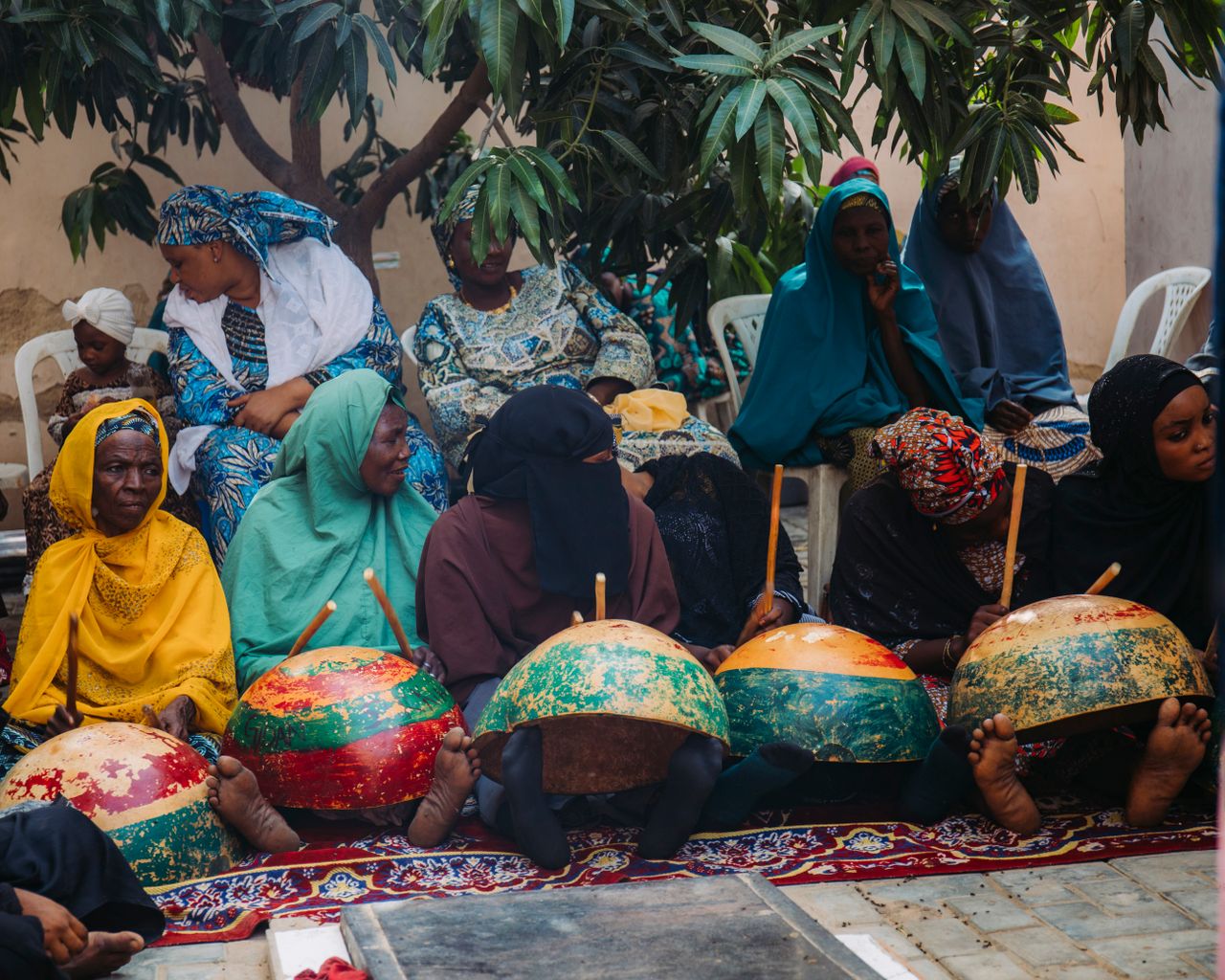 hero-img-02 Women in traditional attire gather for a cultural event in Kano, Nigeria, showcasing community traditions.